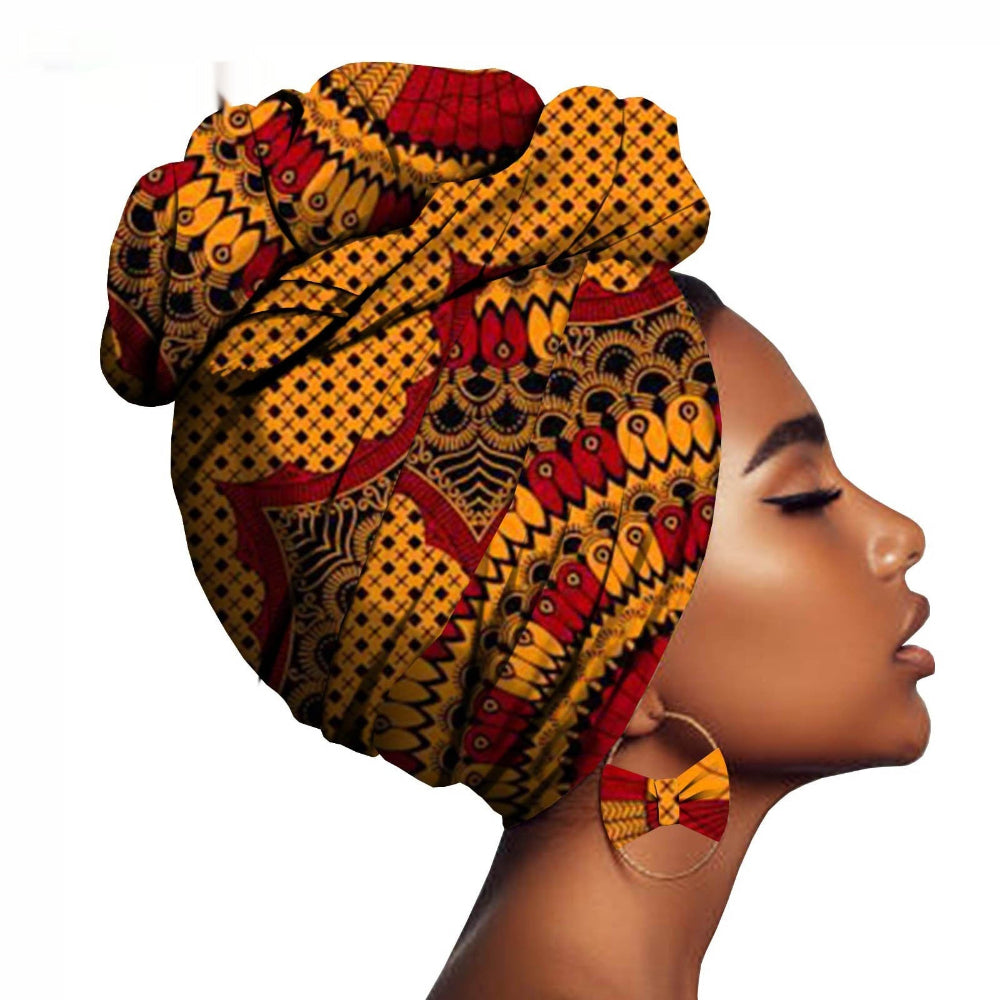 Woman wearing a colorful patterned headwrap and earrings on a white background